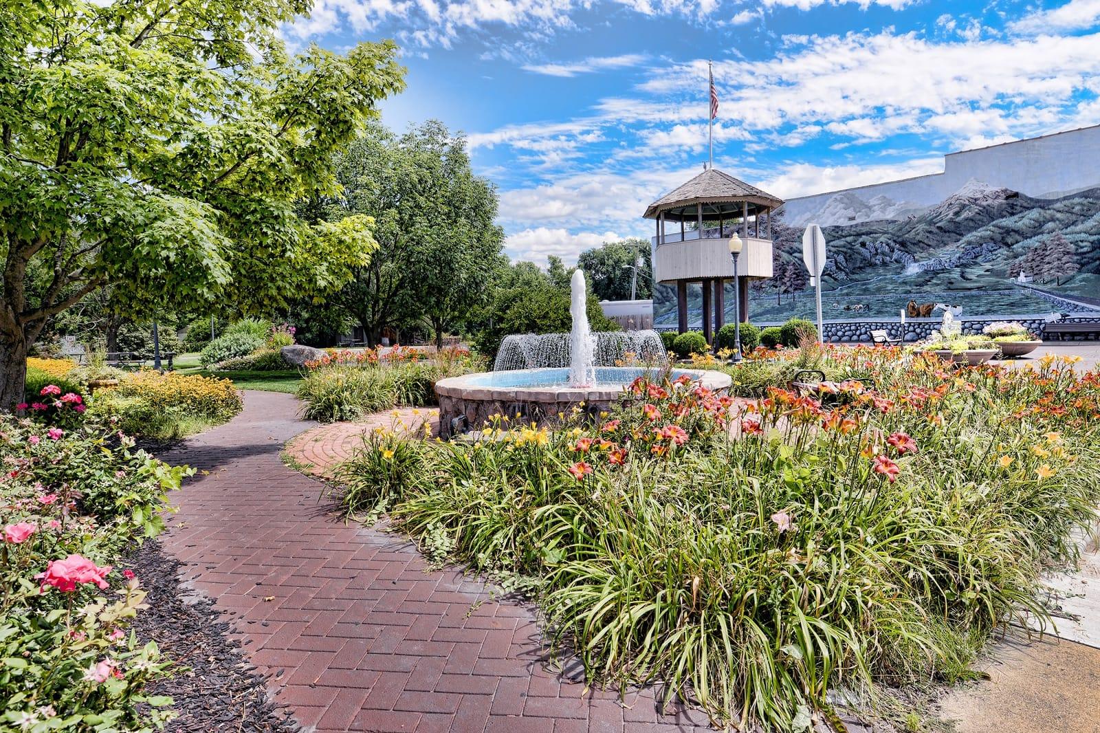 Brick path, fountain, and gazebo at Mural Park with the painted mountain mural behind